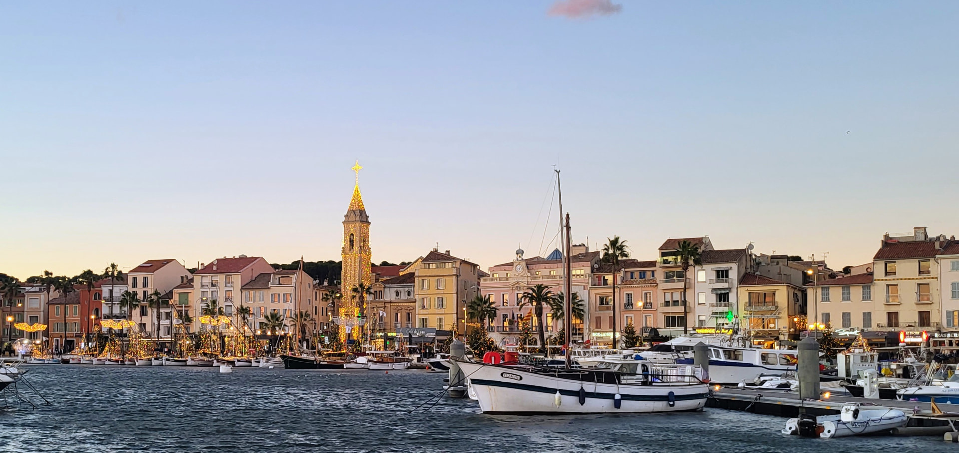 Sanary-sur-Mer harbour at dusk, the church tower lit gold above the moored boats