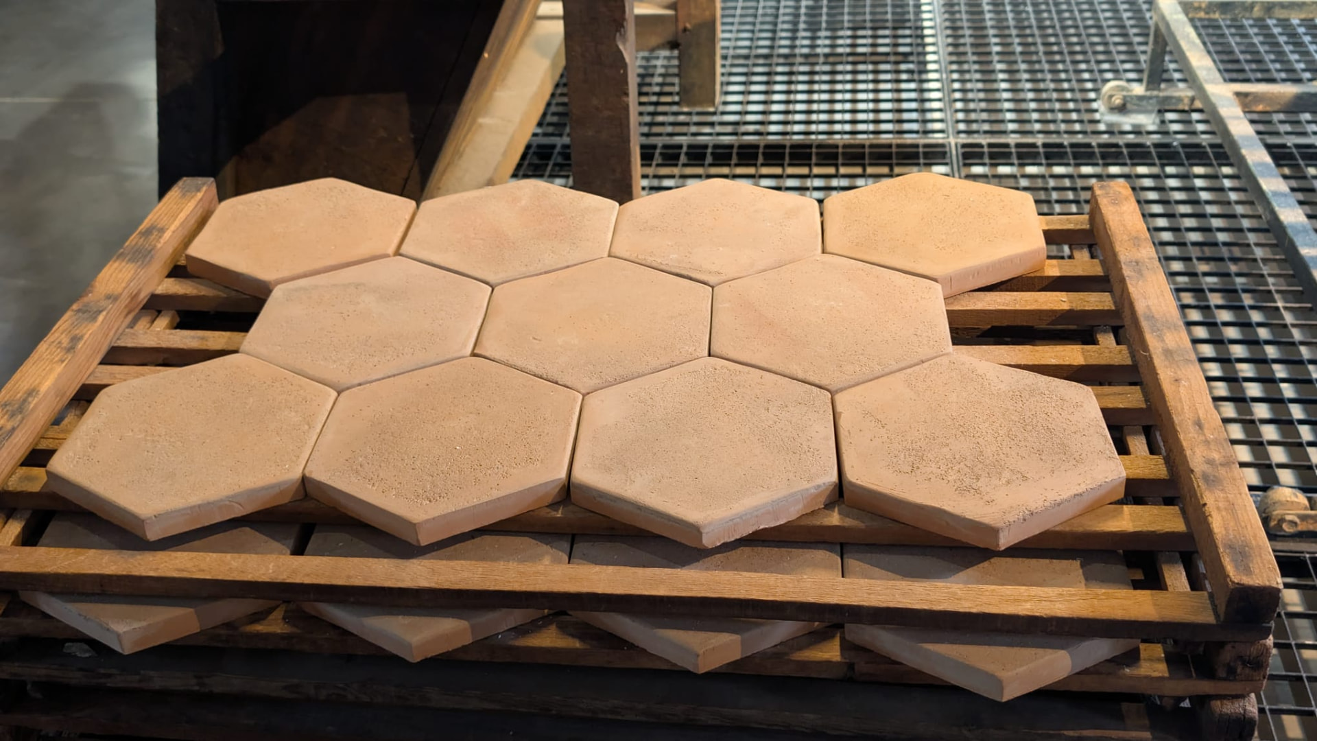 Freshly made hexagonal terracotta tomettes drying on wooden racks in Salernes